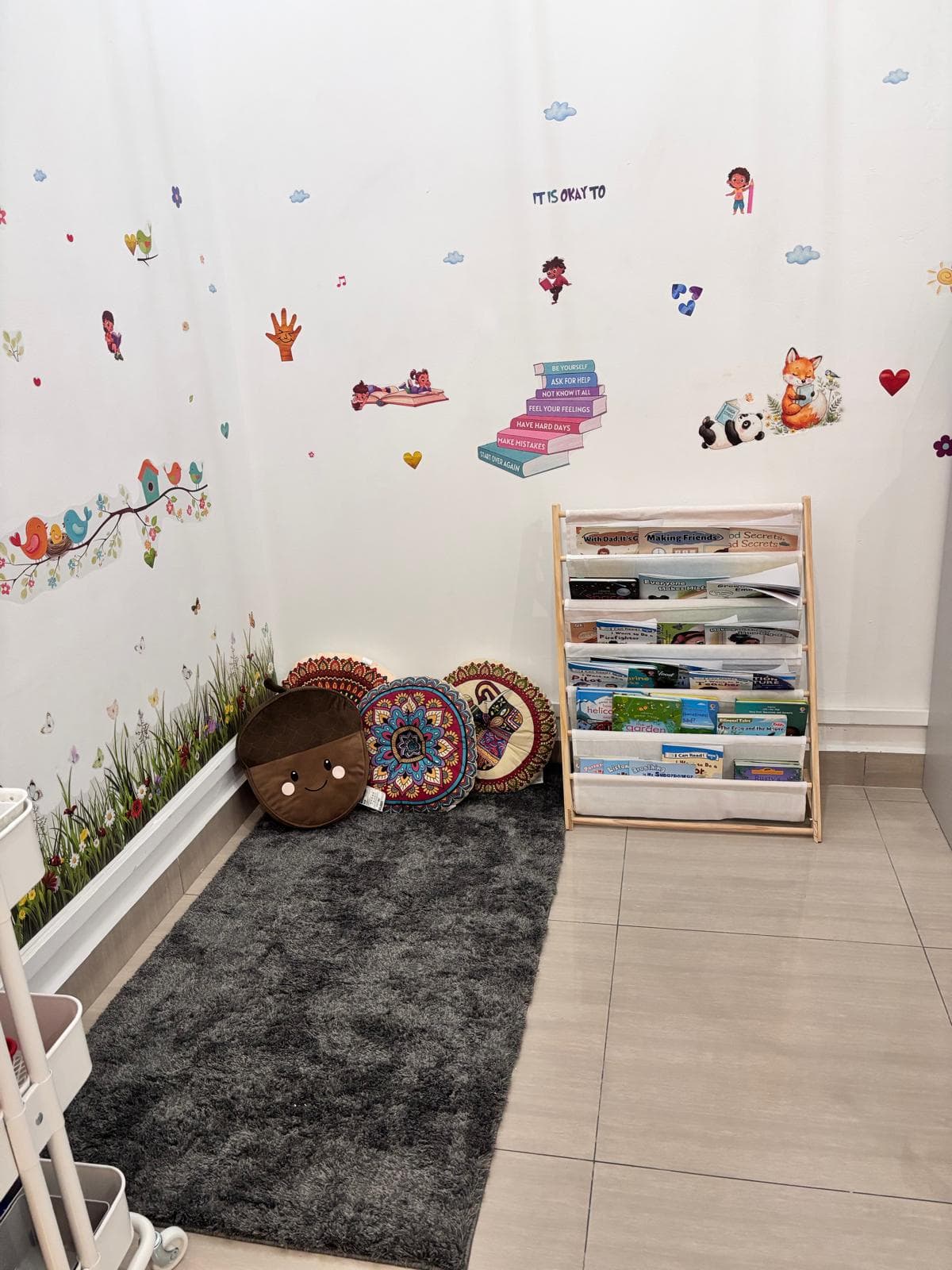 Reading corner with a bookshelf of children's books, a soft rug and floor cushions